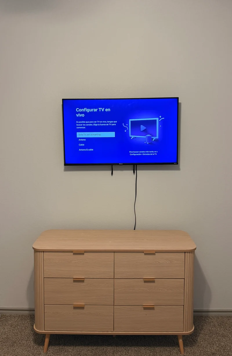 Wall-mounted TV above a wooden dresser during device setup
