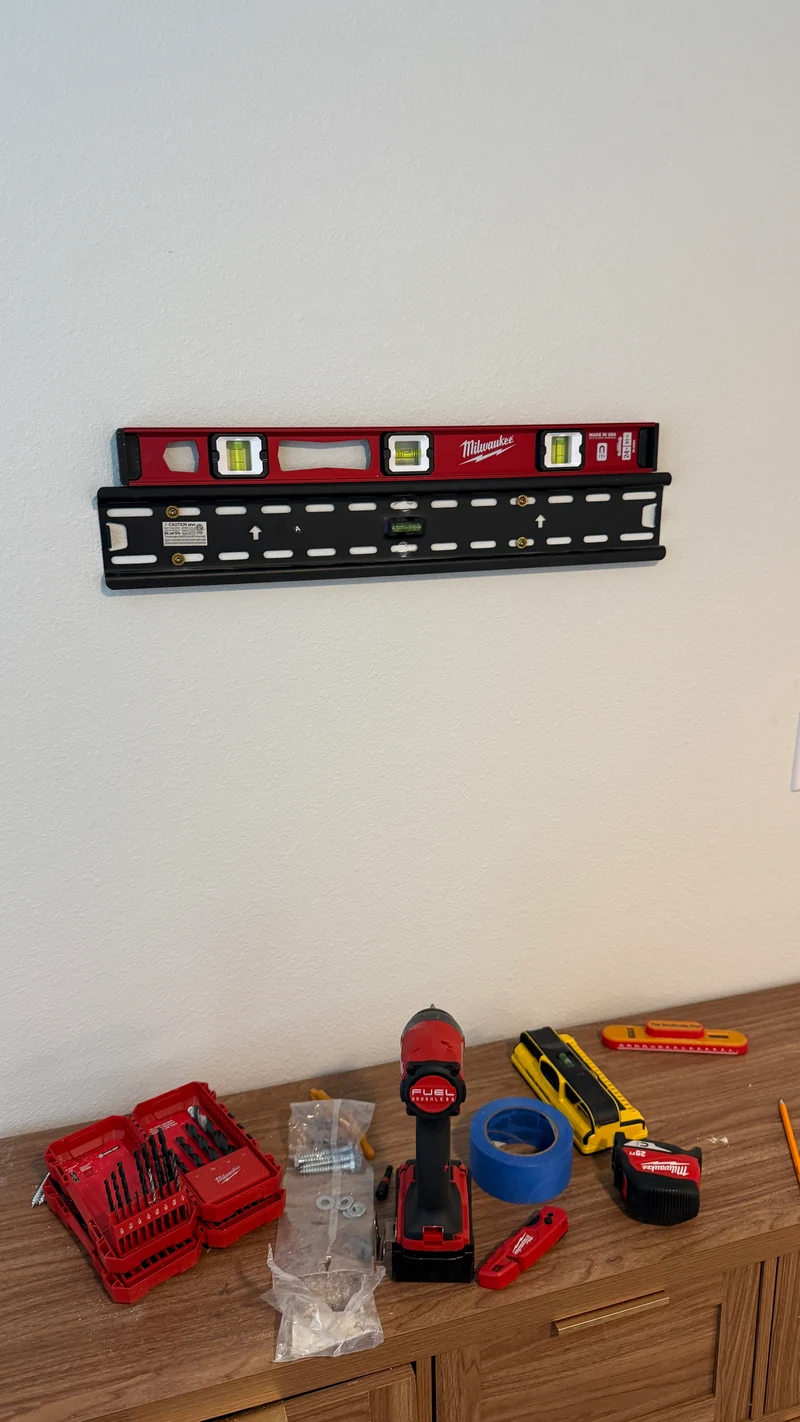 Wall bracket checked with a spirit level, with installation tools on the dresser below