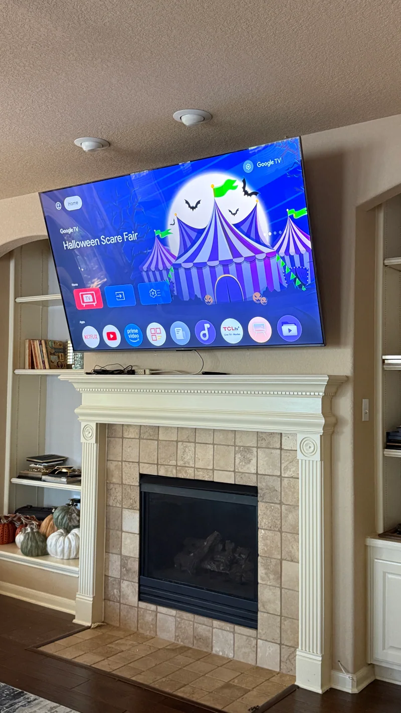 TV installed above a fireplace with visible cables on the mantel