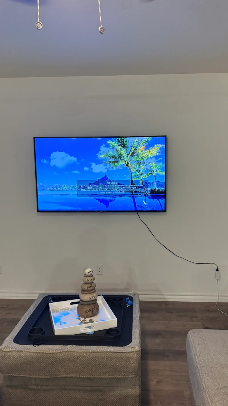 Wall-mounted TV in a living room, with the cable route visible