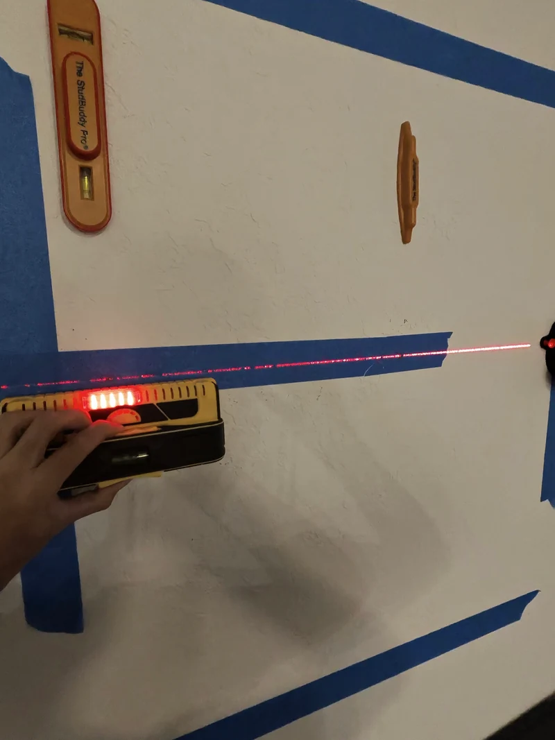 Wall scanner used alongside painter’s tape and a laser line before mounting